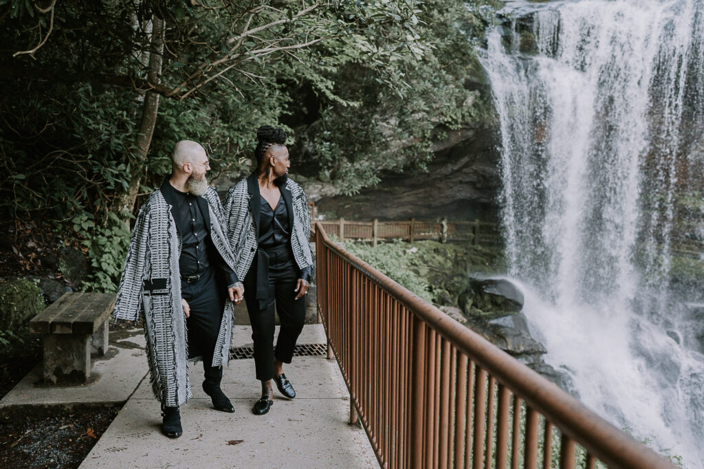 Eloping LGBTQ couple looking at a waterfall near Asheville, NC