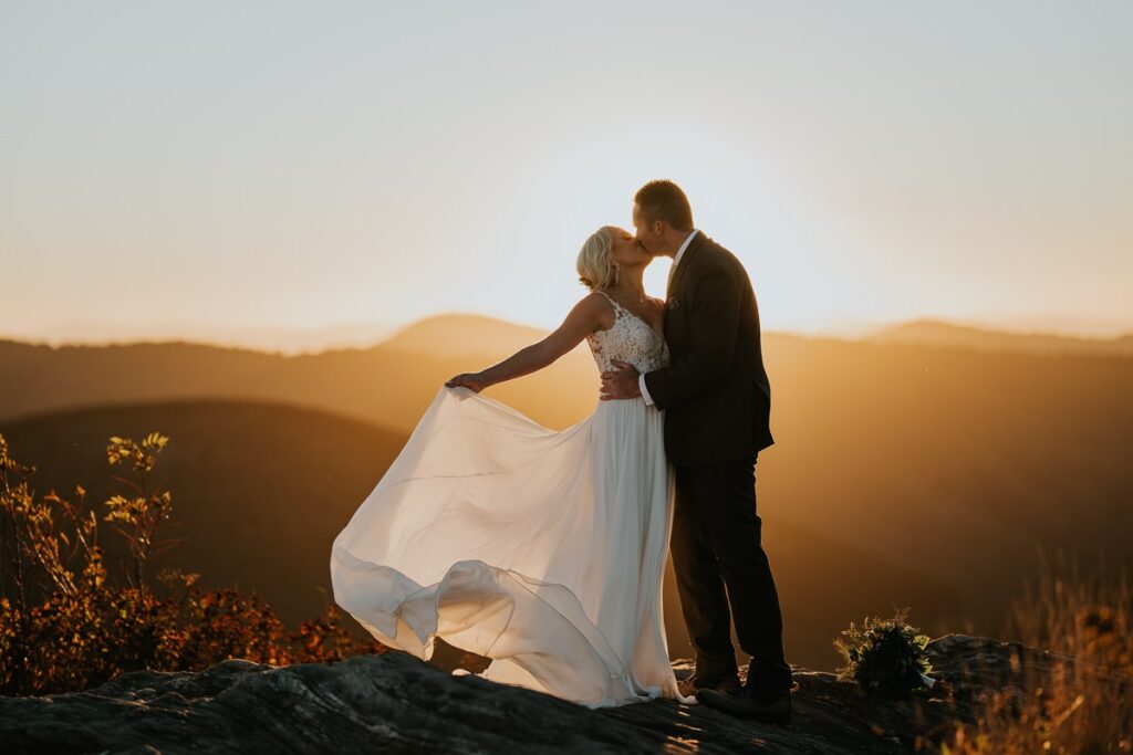 Eloping couple in Pisgah National Forest kissing on a mountaintop